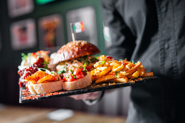 A server presents a platter of delicious gourmet burgers and fries. This image captures a close-up...