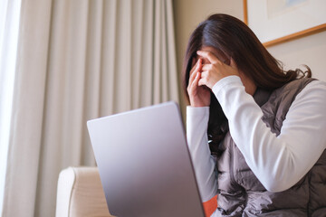 A woman get headache and stressed while working online on laptop computer at home
