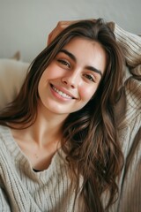 Naklejka premium Young beautiful woman smiling at camera while relaxing at home 