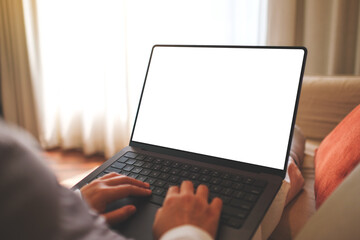 Mockup image of a woman working and typing on laptop computer with blank screen while sitting on sofa at home
