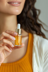 Young woman holding serum bottle with dropper. Beauty, cosmetics and skincare concept. Natural essential oil or favorite cosmetic product in glass bottle with pipette, everyday skin care routine