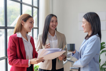 Three asian businesswoman in business attire are smiling and talking to each other