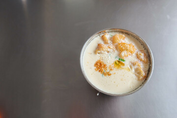 close up of Traditional Chinese breakfast savory soy milk or called salty dou jiang with fried dough bread crullers and spring onion on a silver metal table with copy space taken in a Taiwan