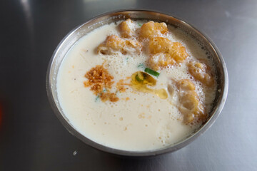 close up of Traditional Chinese breakfast savory soy milk or called salty dou jiang with fried dough bread crullers and spring onion on a silver metal table with copy space taken in a Taiwan