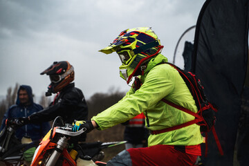 Portrait of a motorcyclist preparing to start a competition in the forest in rainy foggy weather