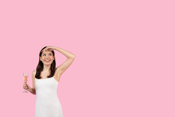 Woman holding champagne looking away on pink background