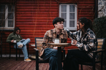 A young and affectionate couple sharing a warm moment over coffee on their home's outdoor patio with a relaxed ambiance.