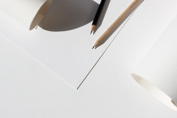 Design Studio Mockup. Sheets of Paper, Graphite Crayons, Paper Rolls Flatlay on Workplace Desk....