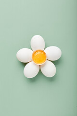 Close up of flower made of eggs with yellow yolk in the center on green background.