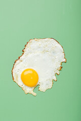 Fried egg with bright yolk on green background.