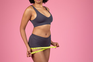 Woman measuring waist with a bright yellow tape measure - 779022173