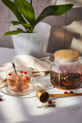 Fruits and berries tea. Glass teapot and cup on the table