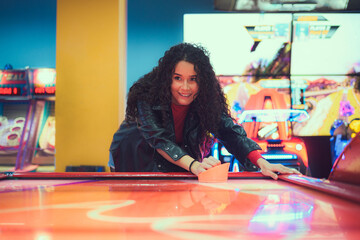 Excited young woman enjoying an air hockey game at a vibrant arcade