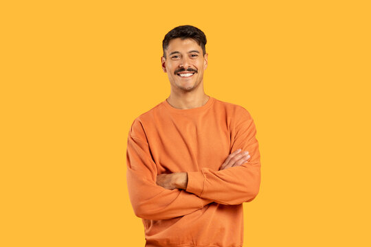 Smiling man with arms crossed on yellow