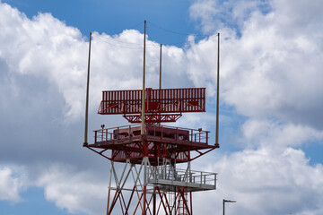 A tower construction with a spinning antenna and clouds on a background  