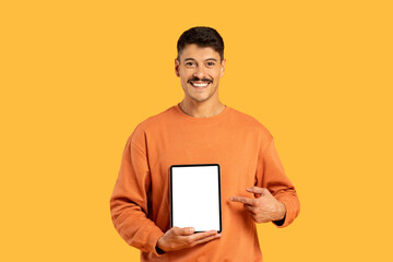 Man holding tablet with blank screen on yellow background