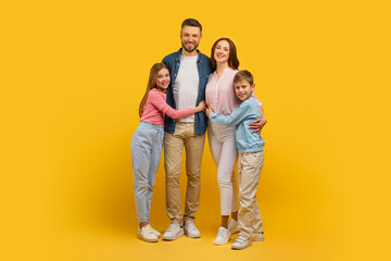 Family portrait with two children smiling on yellow background