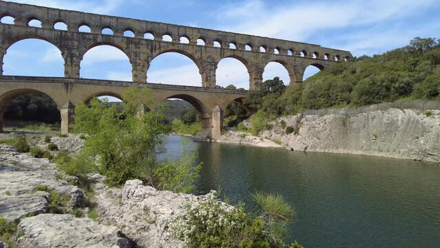 The ancient Pont du Gard Roman aqueduct standing proudly over a tranquil river in Provence, France, a UNESCO world heritage site