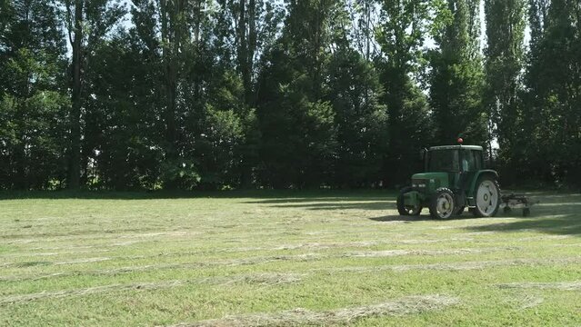 tractor plows the grassy field on a sunny day