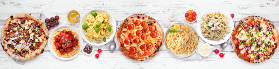 Delicious Italian food table scene. Assorted pizzas and pastas. Overhead view on a white wood banner background. - 779043321