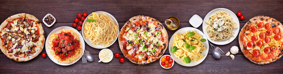 Delicious Italian food table scene. Variety of pizzas and pastas. Above view on a dark wood banner...