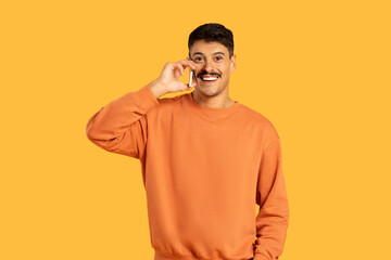 Smiling man talking on phone over yellow background