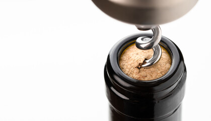 Close-up macro shot of a stainless steel corkscrew inserted into a cork from a wine bottle on a...