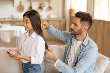 Father styling his daughter's hair, home interior