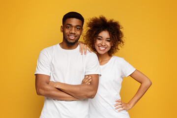 Young african-american couple posing on orange background