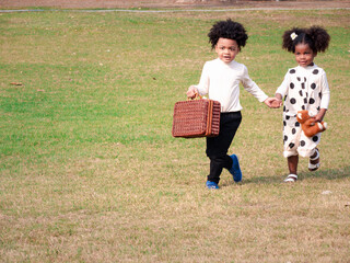 African American boys and girls carries picnic bag in the garden in the beautiful morning. Adventure kindergarten day trip into wild nature.