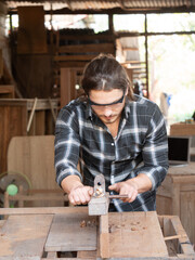 The carpenter using a manual plane for woodworking in his workshop.