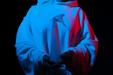 Person in hoodie with spray bottle, under red and blue light effects