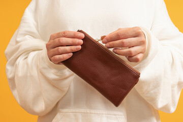 Two hands holding a closed brown wallet with a zipper
