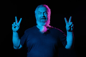 Man displaying a peace sign with each hand, neon blue and pink lights illuminate him