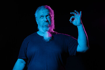 A contemplative man with a hand gesture as if holding something, under neon blue and pink lighting