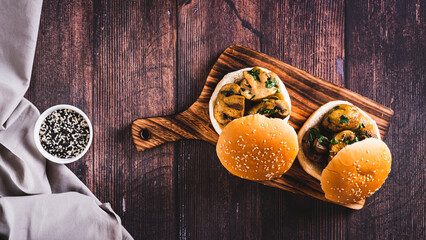 Sliced grilled mushrooms in burger buns on a wooden board top view web banner