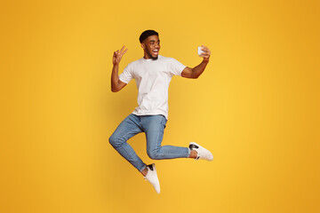 Fototapeta na wymiar Happy man jumping and taking selfie on smartphone