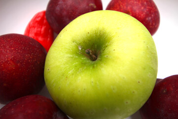 green apple with red plums. group of fruits. green and red fruits.