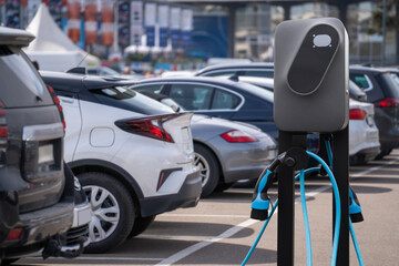 Electric vehicles charging station on a background of a row of cars. Concept. - obrazy, fototapety, plakaty