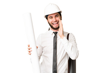 Young architect man with helmet and holding blueprints over isolated chroma key background shouting...