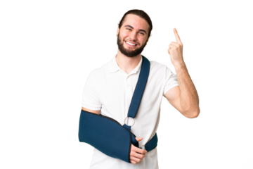 Young handsome man with broken arm and wearing a sling over isolated chroma key background pointing up a great idea
