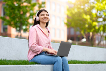 Girl enjoying music while working on laptop