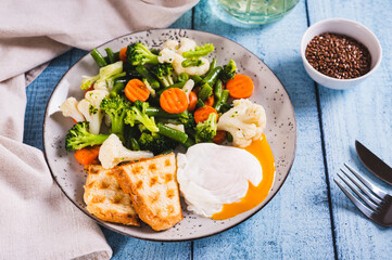 Poached egg, broccoli, cauliflower, green beans and carrots on a plate on the table