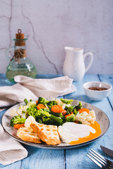 Mix of boiled vegetables, poached egg and waffle toast on a plate on the table vertical view