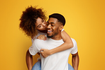 African american millennial couple fooling together, girl kissing her boyfriend