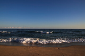 Cielo azul de tarde en la playa con suave oleaje