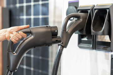 Woman holding plug of electric car charging station