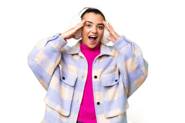 Young woman wearing winter muffs over isolated chroma key background with surprise expression