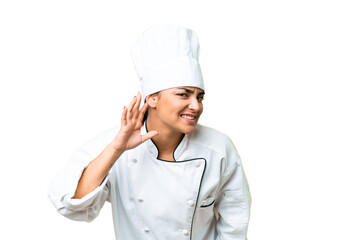 Young woman Chef over isolated chroma key background listening to something by putting hand on the ear