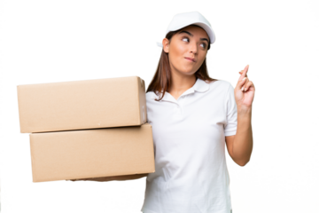 Delivery caucasian woman holding boxes isolated on green chroma background with fingers crossing and wishing the best